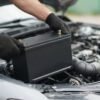 Car battery being fitted into an engine bay (AI-generated illustration)