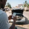 Driver checking a phone beside a car with the bonnet open (AI-generated illustration)